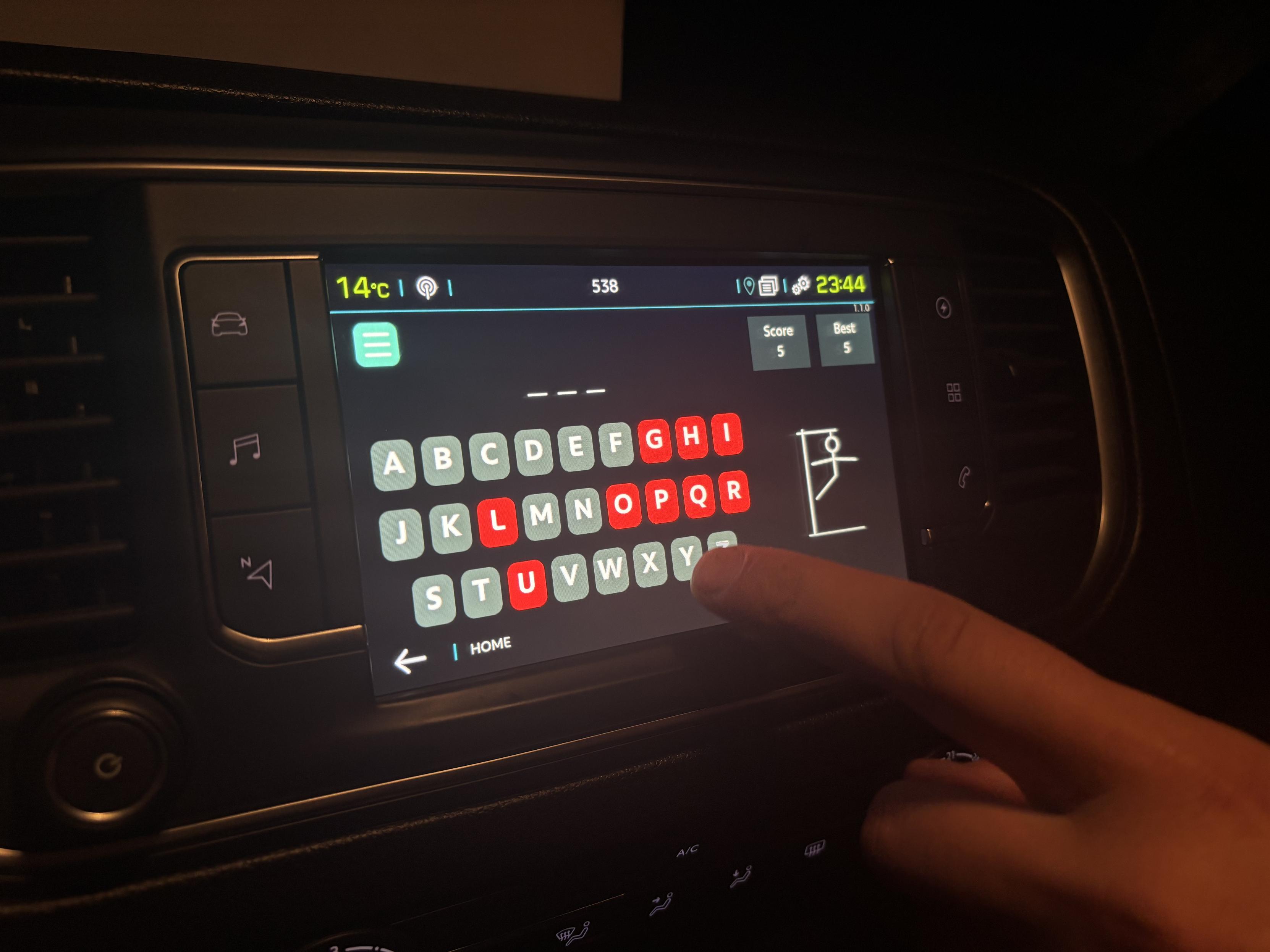 A car infotainment screen with a basic hangman game showing. The player has not got a single letter right and has almost lost.