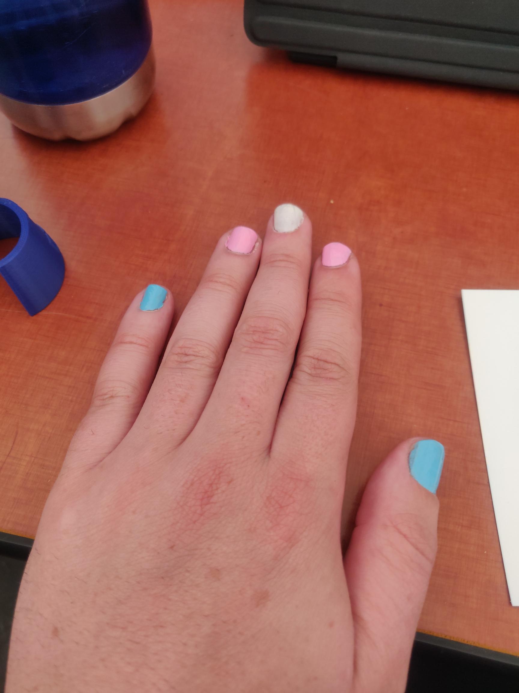 hand with nails painted as the trans flag