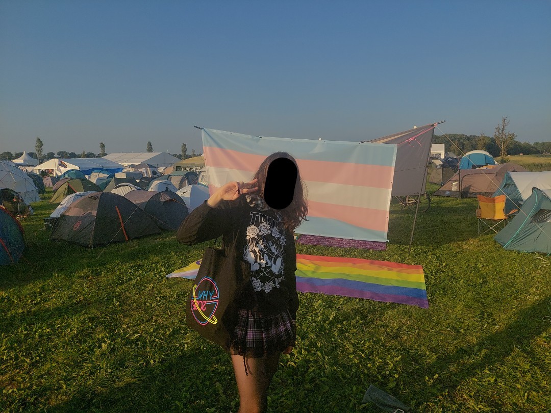 me standing in front of a suspended trans flag and laying on the ground pride progress flag (flags from last pic)